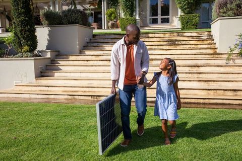Father and Daughter Carrying Solar Panel for Sustainable Energy