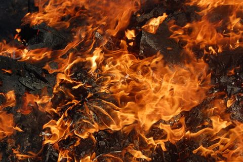 Intense Flames Burning Through Charred Debris in Close-Up Focus