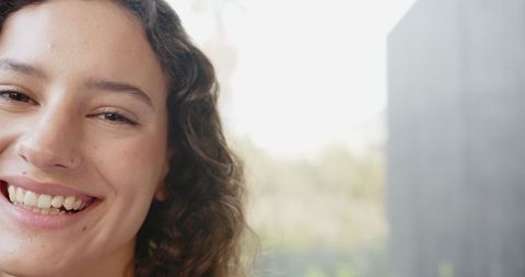 Smiling Woman with Curly Hair in Warm Natural Light by Window
