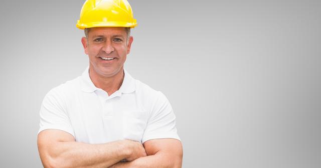 Portrait of worker standing with arms crossed against grey background