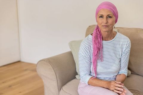 Middle-aged woman in pink headscarf relaxing on sofa