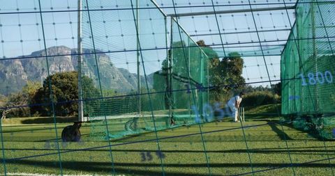 Male golfer practicing swing in outdoor net cage
