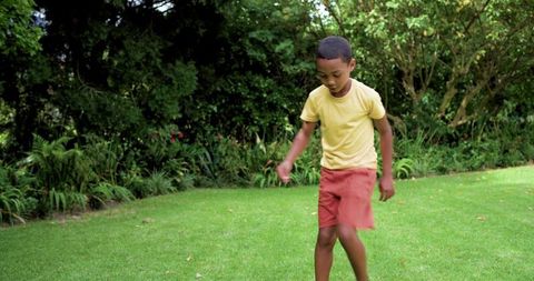 Boy walking barefoot on green lawn exploring garden with animated rings for learning play