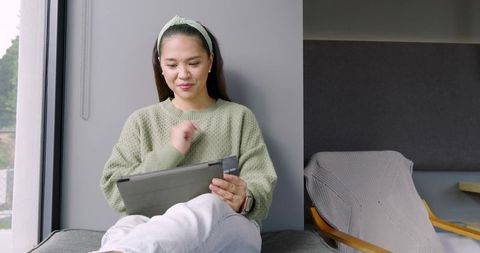 Asian Woman Relaxing with Tablet in Modern Interior
