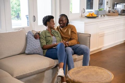 Joyful couple sitting on sofa holding hands at home