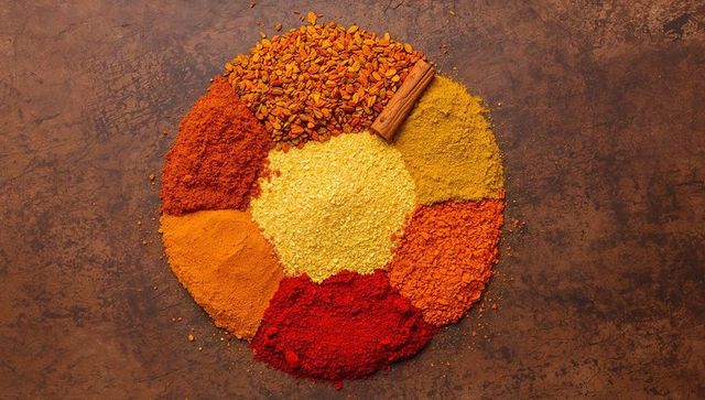 Displaying colorful spice wheel with cinnamon stick and yellow grain on rustic tabletop