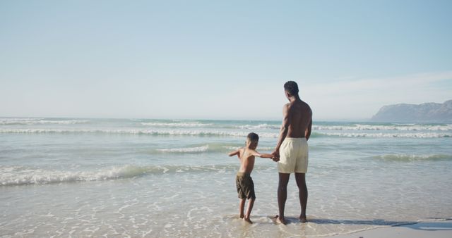 African american father and son holding hands enjoying at the beach. family travel and vacation concept