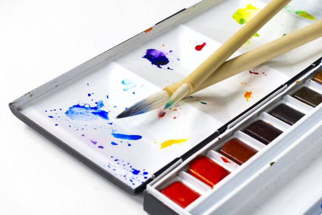 Palette with various watercolor paints and two brushes on white background can be used to depict creativity, art, painting activities, or artistic hobbies in educational or creative projects. Ideal for marketing materials for arts and crafts stores, instructional articles related to painting tutorials, or promoting art workshops and classes.