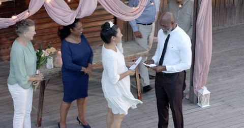 Senior Diverse Couple Exchanging Vows in Garden Ceremony Surrounded by Friends