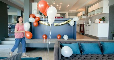 Senior woman arranging balloons for birthday party