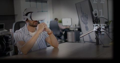 Developer testing vr headset while reviewing 3d robotic hand render in office workspace