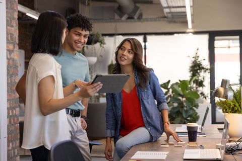 Diverse Team Collaborating Around Desk in Modern Office with Tablet