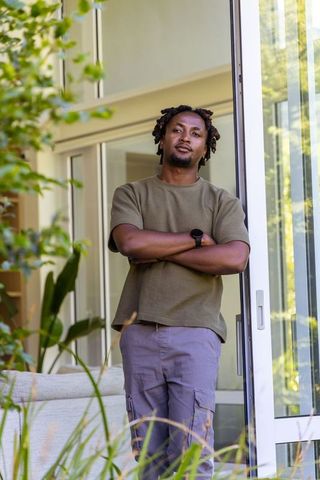 Confident african american man standing in sunlit modern home doorway leaning on frame
