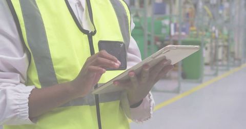 Technician in Safety Vest Using Tablet in Modern Factory