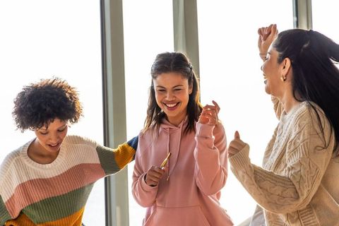 Diverse friends laughing and celebrating together indoors with natural backlight