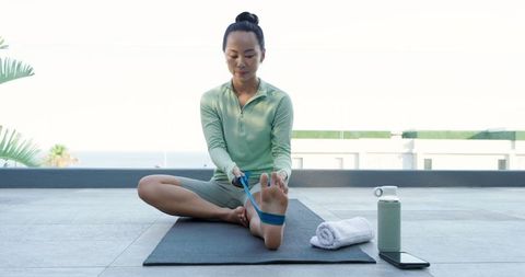 Woman Practicing Stretching Exercise with Resistance Band on Rooftop Terrace