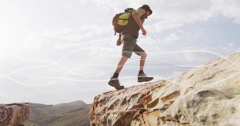 Hiker Traversing Sandstone Cliff in Expansive Desert