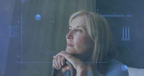 Mature woman gazing thoughtfully while resting chin on chair with blue hud data overlay