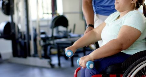 Disabled Woman Exercising with Dumbbell in Gym