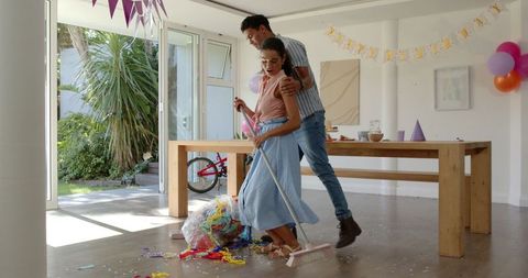 Couple Cleaning Up Birthday Decorations Indoors