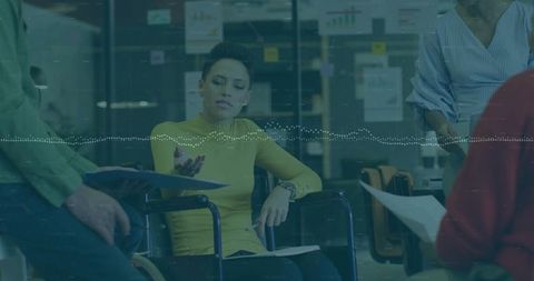 Woman in wheelchair leading office meeting, presenting documents, driving team collaboration