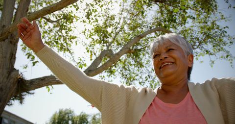 Senior Woman Practicing Yoga Outdoors in Garden, Smiling Serenity
