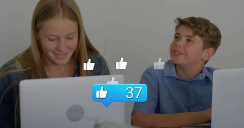 Smiling teens collaborating on laptops in classroom with social media like notification 37