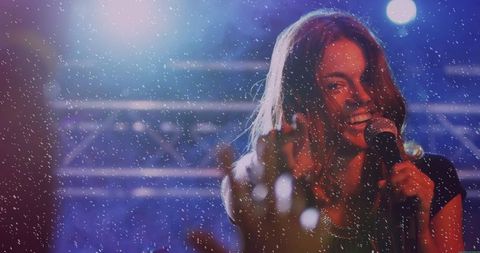 Energetic female singer performing on stage amid sparkling lights