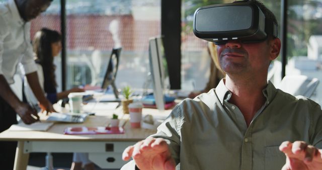 Businessman wearing virtual reality headset interacting during work in a modern office. Ideal for use in contexts associated with technology, innovation, workplace productivity, and the integration of digital tools in professional environments.