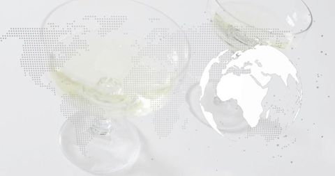 Global cocktail network showing stemmed glasses with pale drink, ice and world map overlay