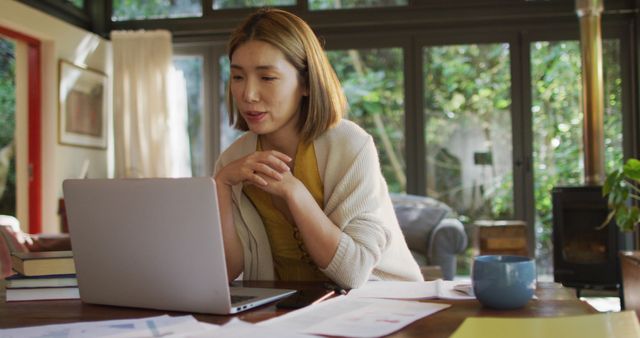 Asian woman sitting at table working from home and using laptop. at home in isolation during quarantine lockdown.