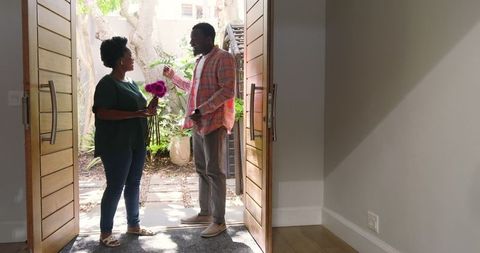 Smiling Couple Sharing Flowers at Doorway in Warm Light