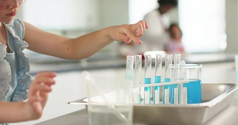 Young girl conducting colorful science experiment with test tubes and beakers