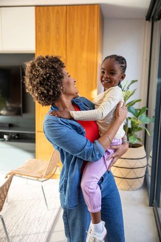Mother Holding Daughter Smiling in Modern Living Room