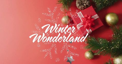 Red winter wonderland flatlay featuring gift, gold ornaments, pine sprigs and glitter