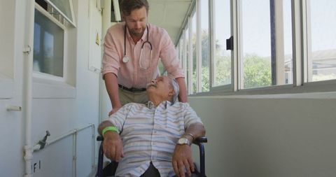 Doctor assisting senior patient in wheelchair at retirement home