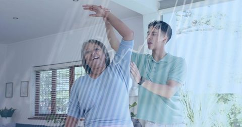 Young caregiver assisting senior woman with shoulder mobility exercise in bright home
