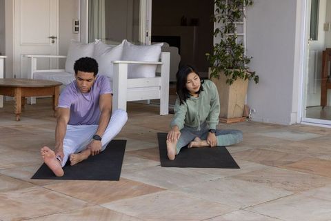 Diverse Couple Practicing Yoga Stretches on Sunny Patio