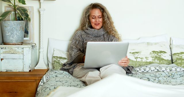 Smiling Mature Woman Using Laptop in Cozy Bedroom - Download Free Stock Images Pikwizard.com