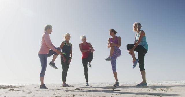 Diverse women wearing sports clothes warming up and stretching at beach. Sport, friendship, healthy and active lifestyle.