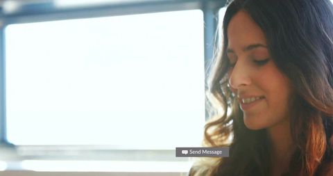 Serene Woman Sending Message in Sunlit Home Office by Window