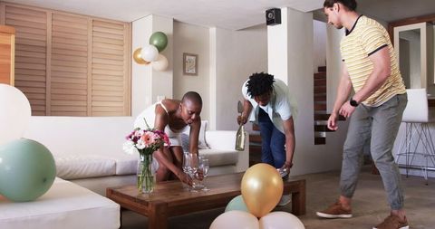 Friends preparing for home celebration arranging balloons and glasses