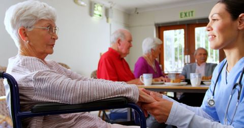 Doctor consoling elderly wheelchair user in nursing home