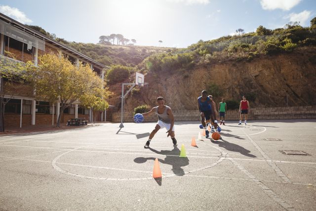 Basketball players practicing dribbling drill  in basketball court outdoors