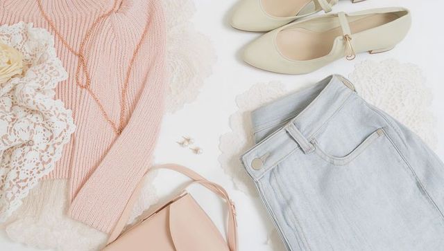 Pastel fashion flatlay featuring pink ribbed sweater, lace, light denim, beige accessories