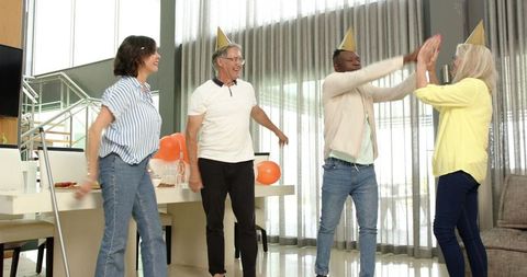 Cheerful group celebrating together with party hats indoors