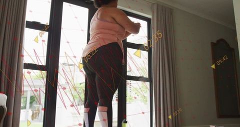 Woman reaching at glass doors during home stretch with fitness data overlay and daylight