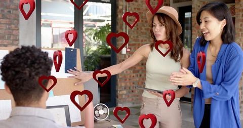 Team placing phone on inspiration board with floating hearts, office collaboration