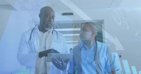 Doctor and Nurse Using Tablet Technology in Hospital Corridor