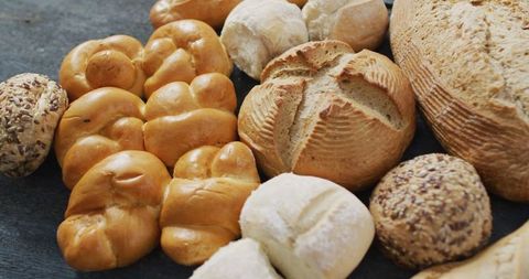 Assorted fresh artisan breads on black wooden background